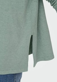 Lichtgroene katoenen top met een relaxte fit, voorzien van zijsplitten en subtiele textuurelementen. Ideaal voor casual draagmomenten.