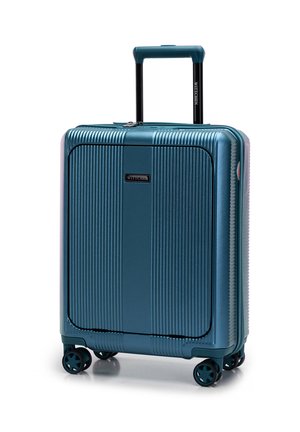 Valise coquée en teal avec texture rainurée verticale, poignée rétractable et quatre roues pour la mobilité. Comprend une étiquette de marque sur le devant.