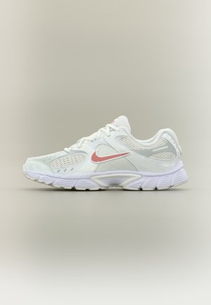 Chaussure de course Nike blanche avec un swoosh rose clair, des panneaux en maille et une semelle rembourrée, vue de profil sur un fond neutre.