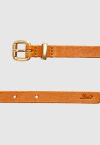 Ζώνη από ταμπά δέρμα με χρυσή μεταλλική αγκράφα. Διαθέτει αρκετές τρύπες για ρύθμιση και ανάγλυφο λογότυπο. Ομαλή υφή με ελαφριά γυαλάδα.