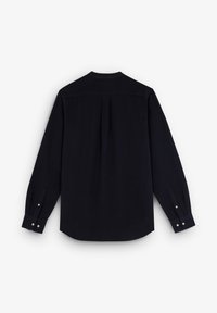 Camisa negra de manga larga hecha de una tela suave, con un pliegue en la espalda, dobladillo redondeado y puños abotonados. Diseño simple y clásico.