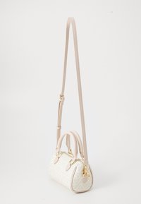 Kleine Handtasche mit einem geometrischen Muster in Weiß und Beige. Hergestellt aus weichem Material, mit zwei Griffen und einem abnehmbaren Schultergurt. Akzente aus goldfarbenem Metall.