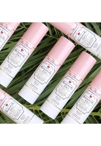 Hangover 3-in-1 sprayflessen, met roze doppen en witte etiketten met zwarte tekst, zijn gerangschikt op groene bladeren.