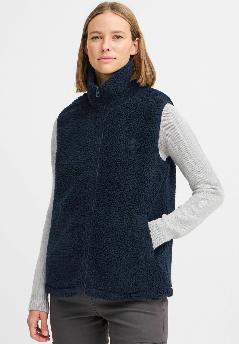 Mörkblå fleeceväst med hög krage, framzip och sidofickor. Texturerad, mjuk tyg med en bekväm utseende. Lagd över en ljus tröja.