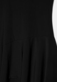 Fekete anyag látható varrással és finom redőzéssel, amely textúrát és enyhe fényességet mutat közeli nézetben.