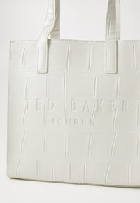 Weiße Kunstleder-Shopper-Tasche mit einem strukturierten Krokodilmuster, ausgestattet mit dem eingeprägten Logo "TED BAKER LONDON" und mittelgroßen Griffen.