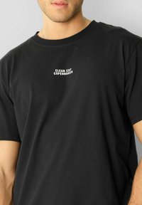 Svart bomull T-skjorte med korte ermer. Har et hvittrykt logo "CLEAN CUT COPENHAGEN" på øvre brystområde.