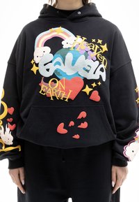 Sudadera corta negra con gráficos coloridos y texturizados que incluyen nubes, corazones, estrellas y el texto "Cielo en la Tierra" en varios estilos.