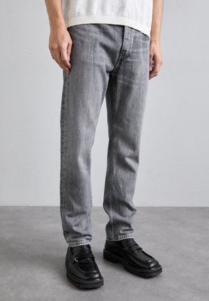Grå denimjeans med rak passform, detaljerad sömnad och femfickdesign, kombinerat med svarta loafers med tjock sula och spänne.