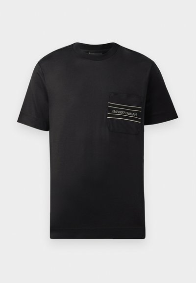 T-shirt preta de manga curta em algodão, com um bolso no peito em destaque que apresenta um logótipo e duas riscas horizontais em branco e dourado.