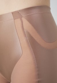 Leggings de cintura alta confeccionados con una tela suave y elástica en color topo, que cuentan con paneles transparentes y acentos de costura curva.