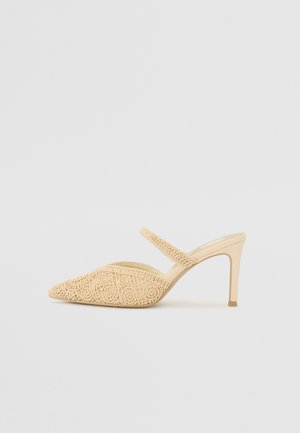 Chaussure à talons ouverte en beige avec un design pointu. Elle présente un motif de dentelle texturé et une fine bride de cheville. Talon lisse.