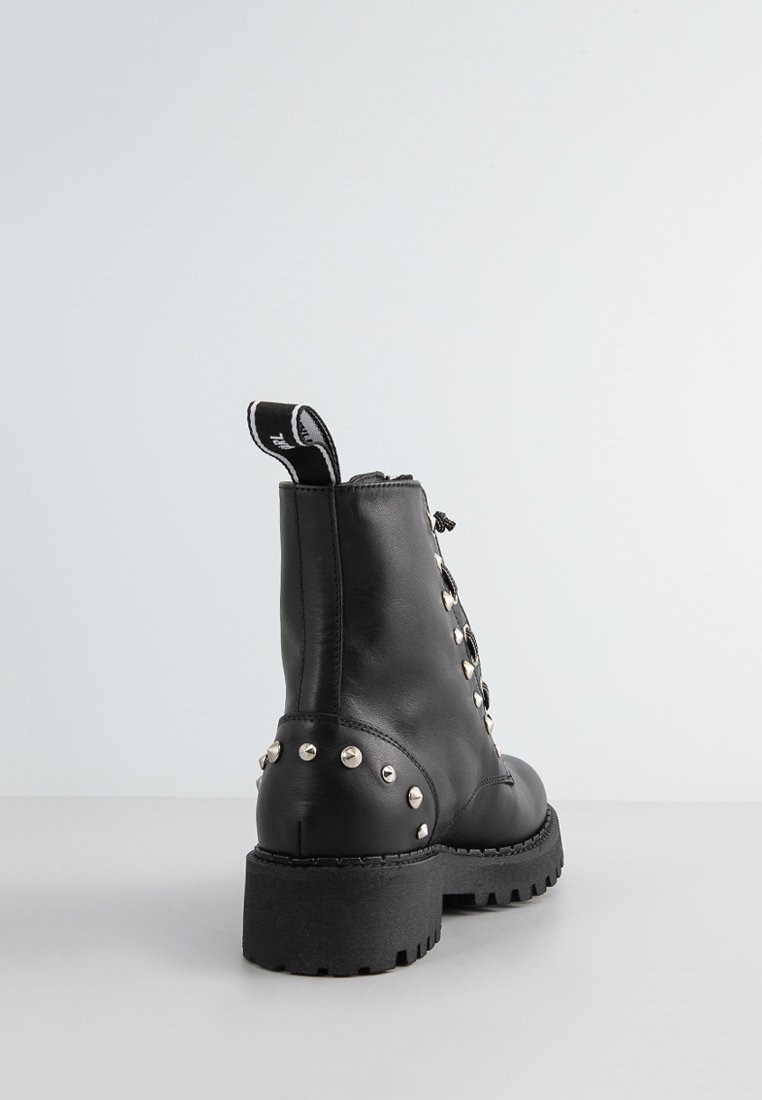 Bottine en cuir noir avec des clous en argent, des lacets et une semelle épaisse. Comprend une fermeture éclair et une languette à l'arrière.