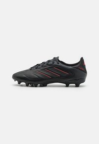 Black soccer cleats with a textured upper, featuring three red stripes on the side and "Copa" branding on the heel. Designed for traction.