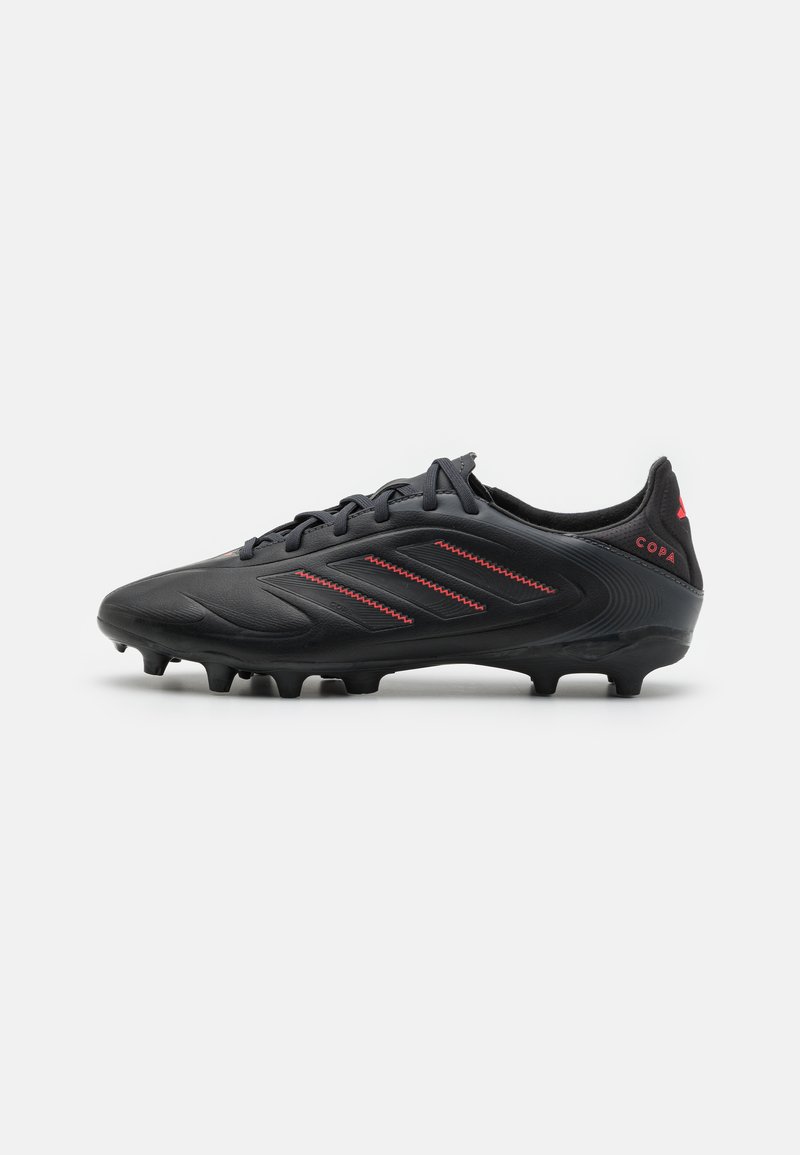 Botas de fútbol negras con parte superior texturizada, que presentan tres rayas rojas en el lateral y la marca "Copa" en el talón. Diseñadas para la tracción.