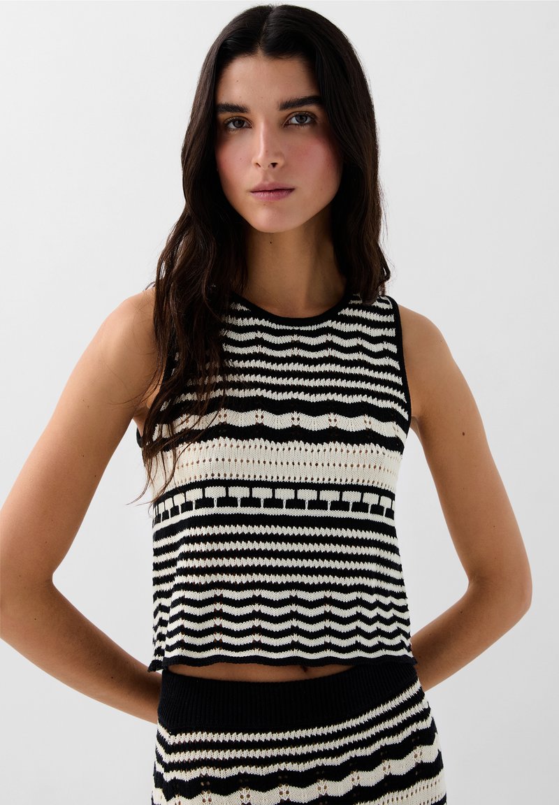 Sort og hvid strikket croptop med vandrette striber, rund halsudskæring og et tekstureret design med varierende mønstre.