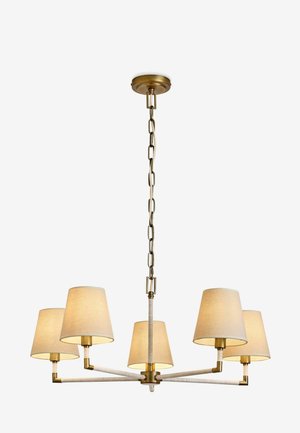 Ceiling chandelier with five beige fabric lampshades, brass arms, and a brass chain suspension against a plain background.