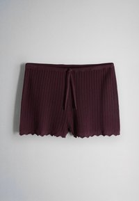 Dark purple knitted shorts with ribbed pattern, drawstring waist, and scalloped hem against a plain light background.