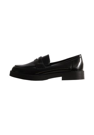 Mocassin noir en cuir avec une bride sur l’empeigne, une semelle épaisse et un talon bloc bas, présenté de profil sur fond blanc.
