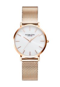 Reloj redondo con una esfera de madreperla blanca, marcadores de hora en oro rosado y una correa de malla en oro rosado. Nombre de la marca "Victoria-Hyde" exhibido.