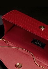 Czerwona torebka kopertówka z imitacji krokodylej skóry z teksturowanym wykończeniem. Wnętrze wykończone gładką tkaniną, z łańcuszkiem w kolorze złotym i kieszenią na zamek.