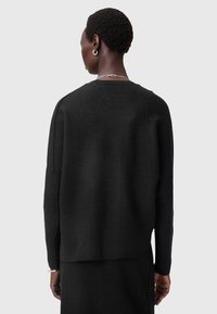 Svart ulltröja med lös passform, ribbad nederkant och sänkt axelsöm. Mjuk textur med en minimalistisk design utan synliga mönster.