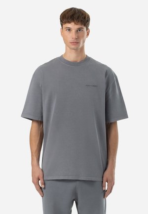 Camiseta de algodón gris con un corte relajado, mangas anchas y cortas, y un pequeño logo bordado en el pecho. Textura suave, diseño minimalista.
