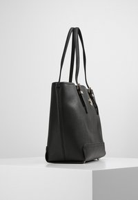 Černá kožená taška přes rameno s dvojitými popruhy, obdélníkového tvaru, hladkou texturou, zlatými kovovými detaily a pevným dnem.