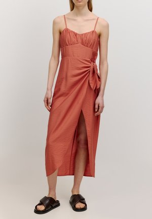 Roestkleurige maxi-jurk met dunne banden, geplooid lijfje, zijsplit en geknoopte detail bij de taille. Draag het met zwarte instapsandalen.