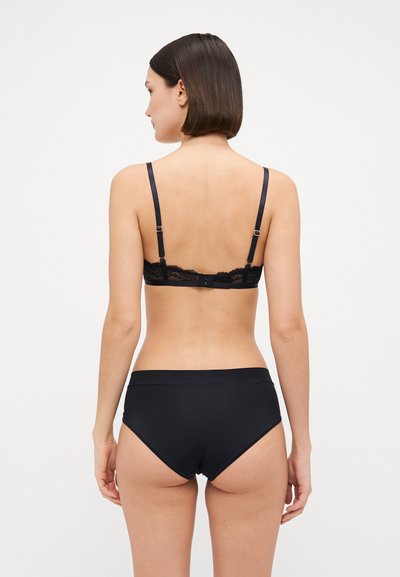 Black lace-back bralette with adjustable straps and a hook closure. High-waisted black brief. Smooth texture and minimal design.