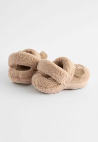 Beige, fluffiga inneskor med dubbla remmar, mjukt material och gummisula. Har en öglad detalj på baksidan.
