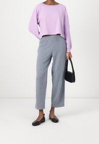 Lyhytlaventeliswtihooli, jossa on pitkät hihat, yhdistettynä harmaisiin leveisiin housuihin. Asusteena pieni musta käsilaukku ja mustat ballerinat.