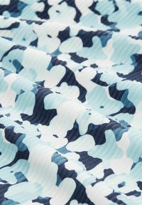 Weicher Stoff mit strukturiertem Rippmuster und einem abstrakten Camouflage-Design in Blau-, Marine- und Weißtönen, dargestellt mit sanften Falten.
