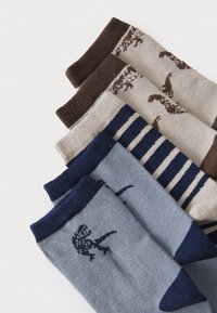 Set von fünf Socken mit verschiedenen Designs: braun mit Tiermotiven, beige mit Mustern, marineblau gestreift und hellblau mit dunklen Akzenten.