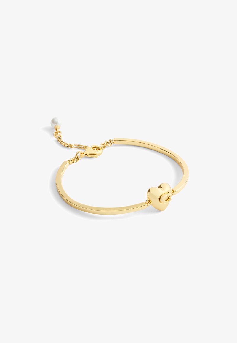 Pulsera de bangle en tono dorado con un diseño liso y minimalista, que presenta un centro en forma de corazón y un acento de perla en una cadena enlazada.