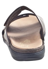 Bruine leren sandaal met een gebogen bandontwerp, open achterkant, geprofileerde binnenzool en een duurzame zwarte rubberen zool.