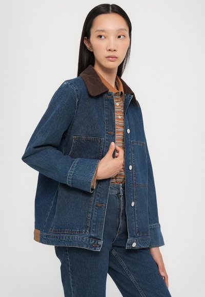 Jeans jakna z rjavim kordurovim ovratnikom, dvema sprednjima žepoma in srebrnimi gumbi, kombinirana z majico z vzorcem in kavbojkami.