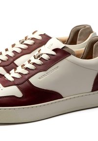 Weiße und burgunderrote Leder-Sneaker mit strukturierten Details, flachen weißen Schnürsenkeln und einem gepolsterten Kragen. Mit eingeprägtem Branding an der Seite.