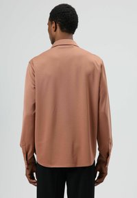 Langärmeliges Hemd aus weichem, staubigem Rosa mit spitzem Kragen, geknöpften Manschetten und lockerer Passform, mit glatter Textur.