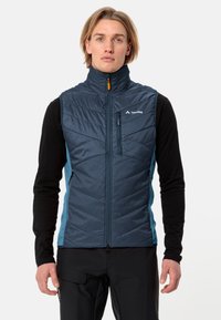 Gilet isolato blu con motivo a cuciture verticali e colletto alto. Presenta una chiusura frontale con zip e pannelli laterali azzurri a contrasto.
