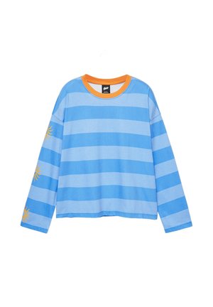 Chemise à manches longues avec larges rayures horizontales bleues, encolure ronde orange et motifs de soleil jaunes sur la manche gauche.