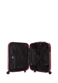 Valigia rigida rossa con una superficie texturizzata, quattro ruote e un interno con zip che presenta tasche e cinghie nere per l'organizzazione.