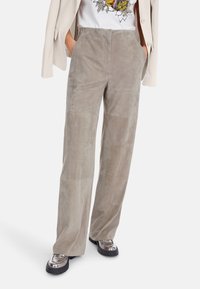 Grau Wildledershorts mit glatter Textur, genähten Paneelen und seitlichen Taschen, kombiniert mit metallicfarbenen Plateauschuhen.