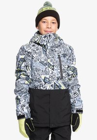 Veste de ski colorée avec des motifs abstraits en noir et blanc, des accents verts et une section inférieure noire. Comprend une poche zippée et des détails aux poignets.