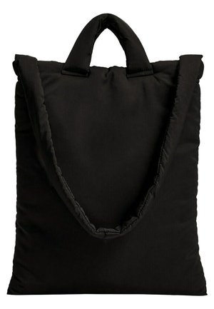 Sac cabas noir matelassé avec des poignées courtes et une large bandoulière sur fond blanc.