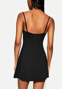 Schwarzes Sommerkleid mit dünnen verstellbaren Trägern, einem figurbetonten Oberteil und einem ausgestellten Rock. Glatte Textur und minimalistisches Design, keine Muster oder Verzierungen.