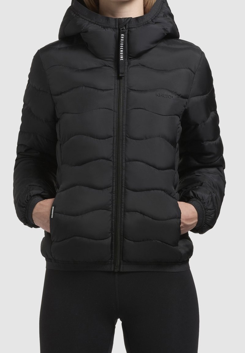 Czarna pikowana kurtka z zapięciem na zamek z przodu i kapturem. Posiada falisty wzór pikowania i elastyczne mankiety. Logo umieszczone po lewej stronie na piersi.