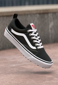 Schwarze Low-Top-Sneaker mit weißem Sidestripe, weißen Schnürsenkeln und Vans-Logo. Verfügt über ein strukturiertes Material, eine Gummisohle und minimalistische Akzente.