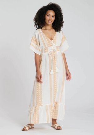 Vestido maxi blanco con patrones geométricos naranjas, escote en V, mangas amplias, cintura ajustable con cordones y borlas, y dobladillo en capas.