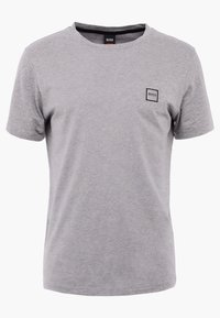 Šedé bavlněné tričko s krátkými rukávy, kulatým výstřihem a malou čtvercovou nášivkou na levém prsu. Měkká textura, neformální design.